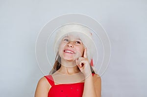 little cute girl is standing in a Christmas hat and surprised at the holiday