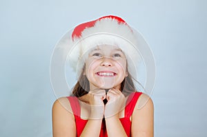 little cute girl is standing in a Christmas hat and surprised at the holiday