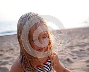 little cute girl in a striped swimsuit lies on a sandy beach