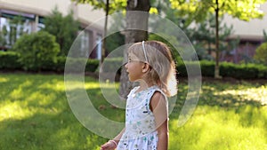 A little cute girl in a summer light dress playing with soap bubbles in the Park