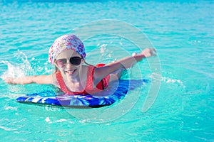 Little cute girl swimming on a surfboard in the