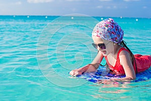 Little cute girl swimming on a surfboard in the