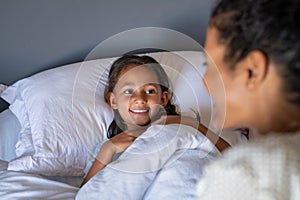 Little cute girl talking to mother in bed