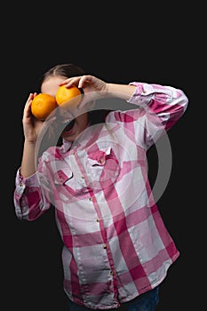 Little cute girl with tangerines posing in the studio on a black background