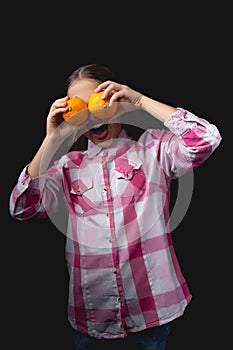 Little cute girl with tangerines posing in the studio on a black background