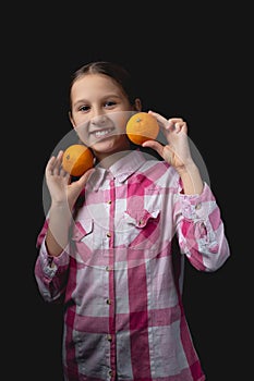 Little cute girl with tangerines posing in the studio on a black background