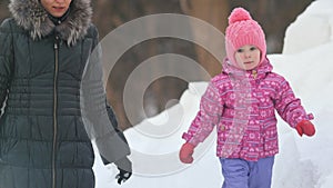 Little cute girl walking in the snow for a walk with her mom