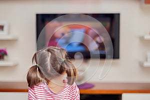 Little cute girl watching television with attention