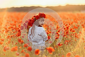 Little cute girl in white dress playing field poppy wreath with a bouquet of poppies in her hands