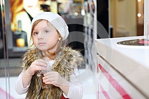 Little cute girl in white hat holds bottle of