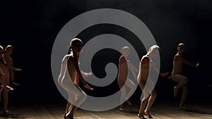 Little cute girls dancing ballet on theater stage on black background in smoke.