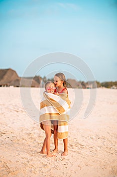 Little cute girls wrapped in towel at tropical beach. Kids on the beach vacation