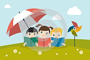 Little cute group of three children reading a books sitting on the grass under sun umbrella.