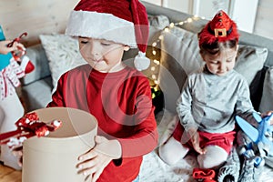 Little cute happy boy in red Christmas santa claus hat with gift in hands from family, parents.Playing kids, congratulations,