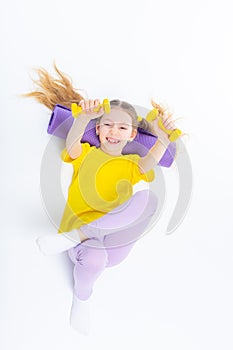 Little cute happy girl lies with dumbbells and gymnastic mat. Isolated on white background. View from above.