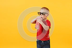 Little cute kid baby boy 3-4 years old in red t-shirt, 3d imax cinema glasses holding plastic glass of soda, drinking