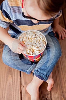 Little cute kid baby boy 2-3 years old , 3d imax cinema glasses holding bucket for popcorn, eating fast food on wooden background