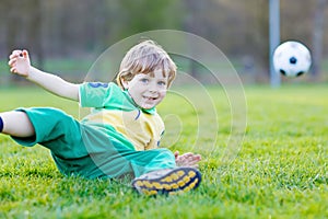Little cute kid boy of 4 playing soccer with football on field, outdoors