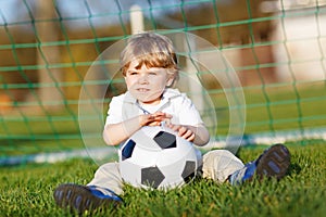 Little cute kid boy of 4 playing soccer with football on field, outdoors