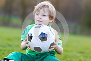 Little cute kid boy of 4 playing soccer with football on field, outdoors