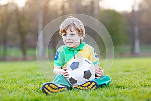 Little cute kid boy of 4 playing soccer with football on field, outdoors