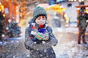 Little cute kid boy drinking hot children punch or chocolate on German Christmas market. Happy child on traditional