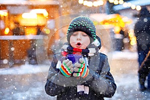 Little cute kid boy drinking hot children punch or chocolate on German Christmas market. Happy child on traditional