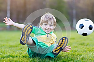 Little cute kid boy of 4 playing soccer with football on field, outdoors