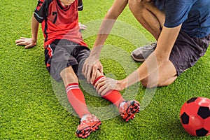 Little cute kid boy in red football uniform and his trainer or father playing soccer, football on field, outdoors