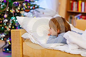 Little cute kid boy sleeping under Christmas tree