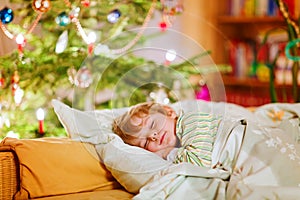 Little cute kid boy sleeping under Christmas tree