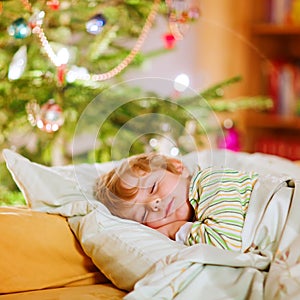 Little cute kid boy sleeping under Christmas tree