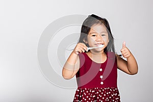 Little cute kid girl 3-4 years old smile brushing teeth and show thumb up finger for good sign