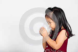 Little cute kid girl 3-4 years old smile holding milk glass he drinking white milk