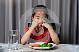 Little cute kid girl refusing to eat healthy vegetables. Children do not like to eat vegetables