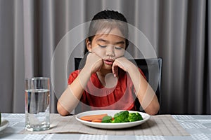 Little cute kid girl refusing to eat healthy vegetables. Children do not like to eat vegetables