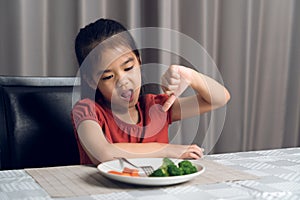 Little cute kid girl refusing to eat healthy vegetables. Children do not like to eat vegetables