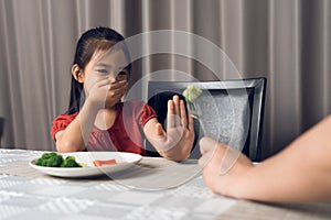 Little cute kid girl refusing to eat healthy vegetables. Children do not like to eat vegetables