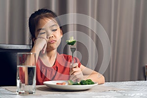 Little cute kid girl refusing to eat healthy vegetables. Children do not like to eat vegetables