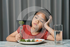 Little cute kid girl refusing to eat healthy vegetables. Children do not like to eat vegetables