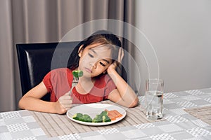 Little cute kid girl refusing to eat healthy vegetables. Children do not like to eat vegetables
