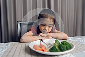 Little cute kid girl refusing to eat healthy vegetables. Children do not like to eat vegetables