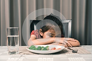 Little cute kid girl refusing to eat healthy vegetables. Children do not like to eat vegetables