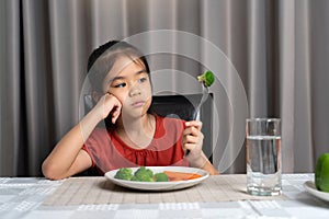 Little cute kid girl refusing to eat healthy vegetables. Children do not like to eat vegetables