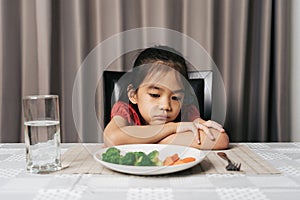 Little cute kid girl refusing to eat healthy vegetables. Children do not like to eat vegetables