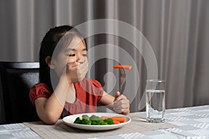 Little cute kid girl refusing to eat healthy vegetables. Children do not like to eat vegetables