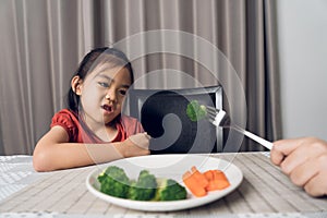 Little cute kid girl refusing to eat healthy vegetables. Children do not like to eat vegetables