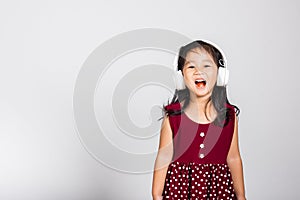 Little cute kid girl 3-4 years old listen music in wireless headphones in studio shot isolated