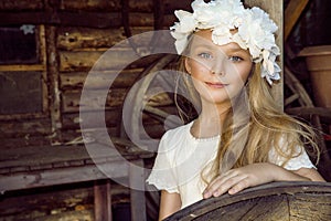 Little cute little girl in a flower garland on her head, standing on the background