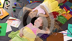 Little cute multiracial friends lying on carpet and laughing, happy childhood